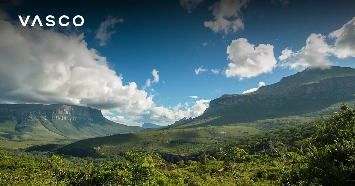 Eine weite grüne Landschaft mit sanften Hügeln und Bergen unter einem blauen Himmel