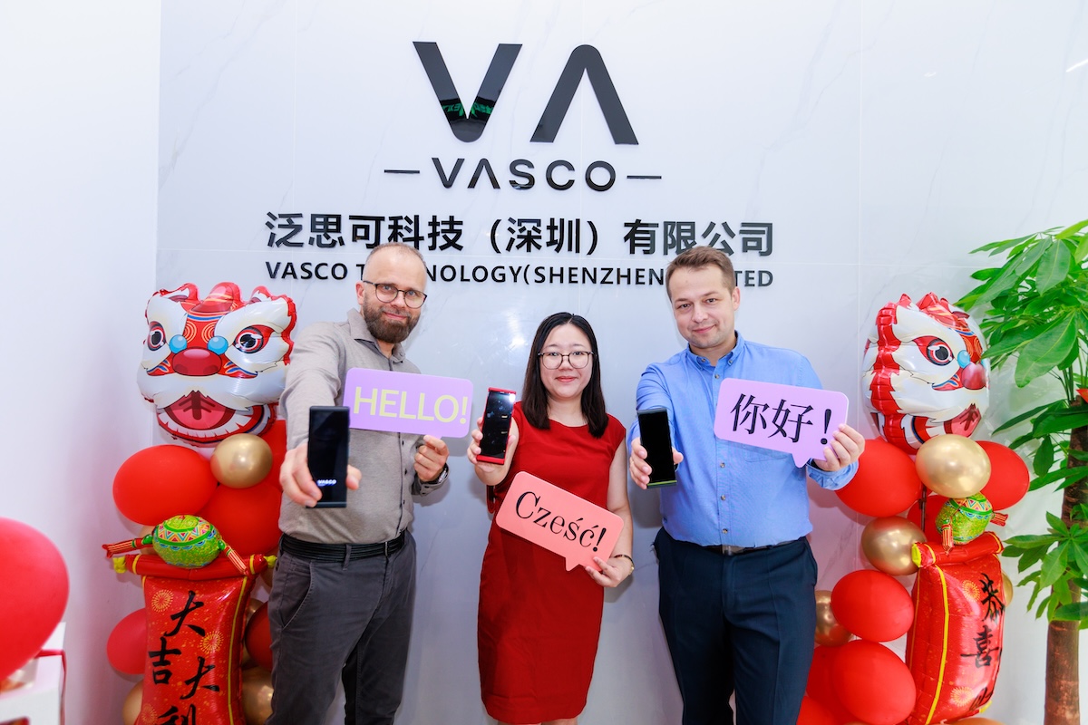 vasco-asien-shenzhen CEO und COO von Vasco auf einer Messe in Shenzhen in China. Zwischen ihnen steht eine Frau. Die Personen halten Vasco Translator und Schilder mit dem Wort