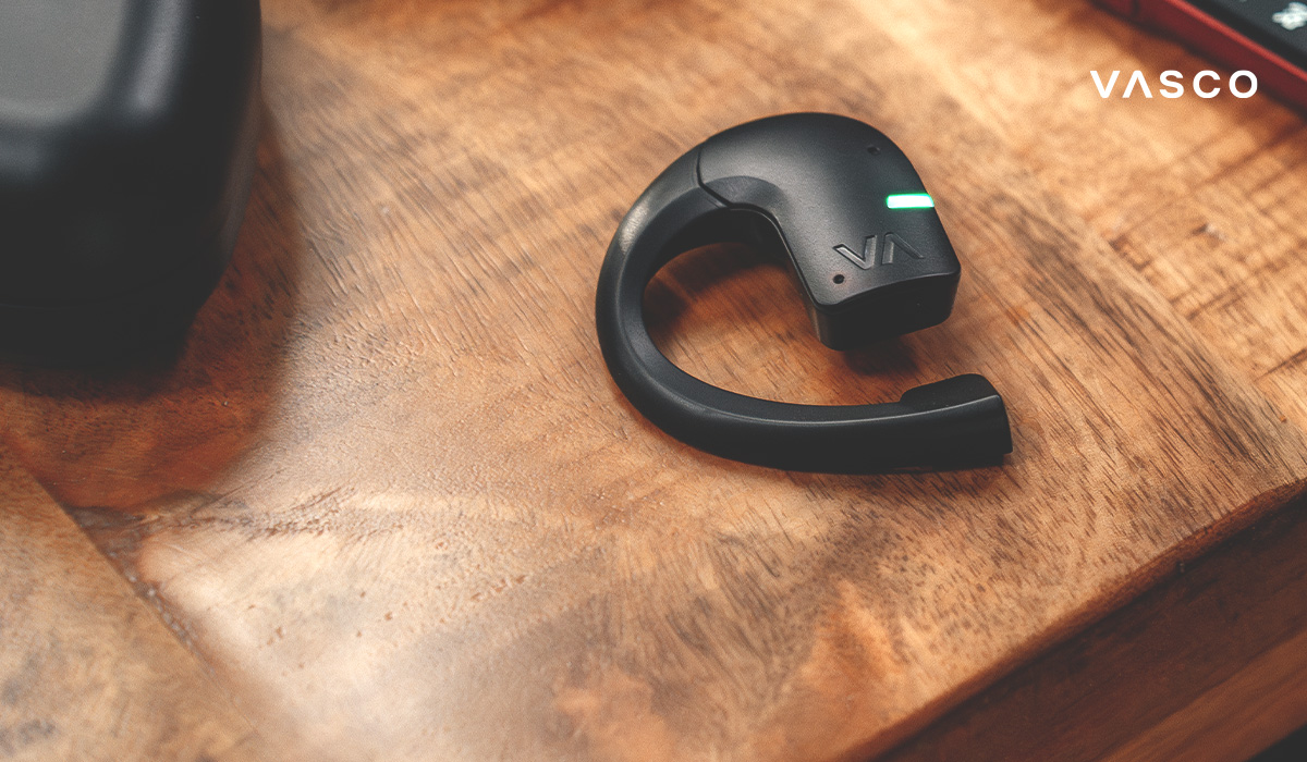 Ein Ohrhörer des Vasco Translator E1 liegt auf einem Tisch.