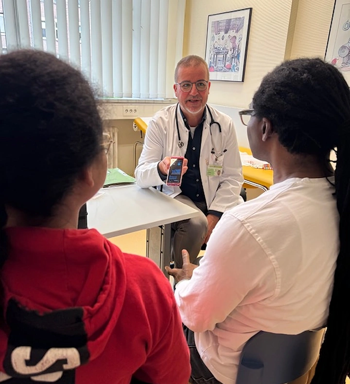 Doctor explaining something to patients while holding a Vasco Translator device.