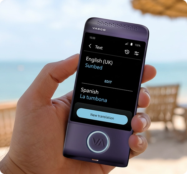 Eine Nahaufnahme einer Hand, die ein violettes elektronisches Übersetzungsgerät der Marke Vasco hält. Auf dem Bildschirm ist eine Textübersetzung vom britischen Englisch ins Spanische zu sehen, wobei das Wort „Sunbed“ mit „La tumbona“ übersetzt wurde. Im Hintergrund ist eine helle, sonnige Strandszene zu sehen, mit einer weichgezeichneten Ansicht des Meeres, goldenem Sand, mehreren Sonnenliegen und einem Stroh-Strandschirm. 