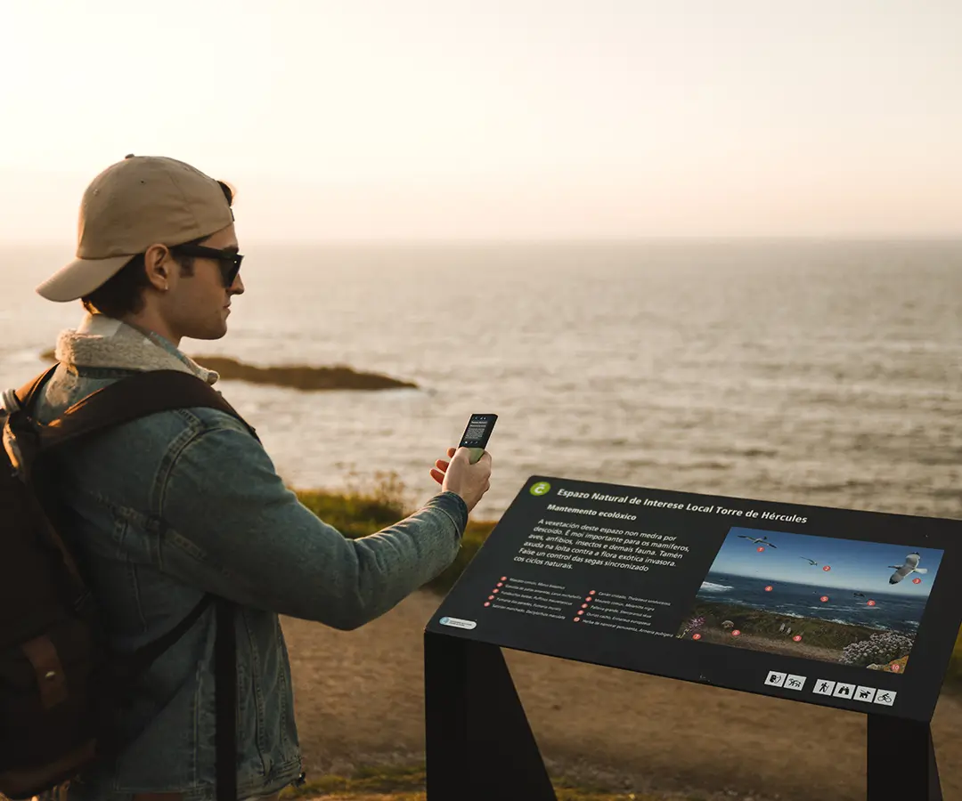 Ein Mann am schönen Meer, der einen Fotoübersetzer benutzt, um ein Schild mit touristischen Informationen über seinen Standort zu lesen